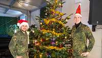 Zwei Soldaten stehen neben einem geschmückten Weihnachtsbaum.