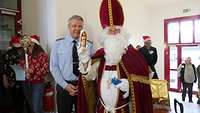 Nikolaus steht mit einem Soldaten zusammen und verteilt Geschenke.
