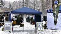 Zu sehen ist der Eingang zum Biwak, zwei Pavillons und Plakate.