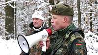 Zwei Soldaten schauen zu den Gästen und einer spricht in ein Megaphon.