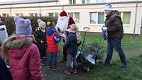 Kinder stehen um den Weihnachtsmann herum.