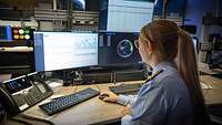 Soldatin sitzt mit Rücken am Schreibtische vor einem Bildschirm