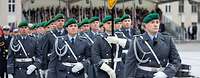 Soldaten im Dienstanzug marschieren auf einem Festplatz ein. Sie tragen eine Deutschlandflagge