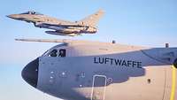 Bundeskanzler Scholz schaut im Flug aus dem Fenster eines A400M, daneben fliegt ein Kampfjet.