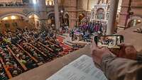 In einem Kirchenraum sitzen viele Menschen