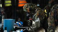 a soldier is wearing an ABC protective mask and gloves. He is dealing with dangerous substances. 