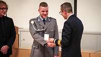 Ein Soldat überreicht einem anderen Soldaten eine weiße Schatulle.