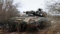 Ein Schützenpanzer Puma fährt mit hoher Geschwindigkeit eine matschige Schotterpiste entlang.