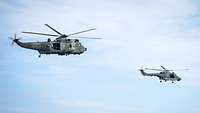 Sea Lynx und Sea King - Hubschrauber der Marineflieger Zwei Militärhubschrauber fliegen versetzt nebeneinander.
