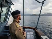 Soldat in Uniform steht in der Nock eines Schiffes und hält Ausschau.