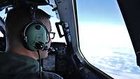 Der Pilot sitzt im Cockpit und blickt auf die Wolken