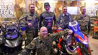 Ein Motorrad der Feldjäger und eine Enduro-Maschine, dahinter posieren fünf Personen