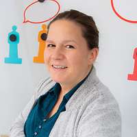 Melanie S. steht vor einem Whiteboard. Vor ihr liegt ein Spiegel – ein Symbol für Selbstreflexion