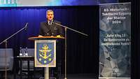 Ein Marinesoldat steht hinter einem Rednerpult und spricht in ein Mikrofon.