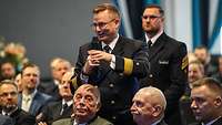 Ein Marineoffizier hält ein Mikrofon in der Hand und spricht
