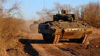 Schützenpanzer fahren hintereinander auf unbefestigten Wegen. 