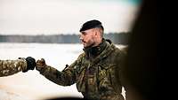 Ein Soldat steht einem weiteren Soldaten gegenüber. Beide grüßen sich per Faustcheck.