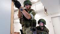 Zwei Militärpolizisten sichern einen Hausflur mit gezogenen Waffen