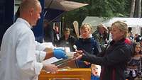Ein Koch gibt Essen an eine Frau aus.