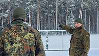 Zwei Soldaten stehen im Schnee. Einer zeigt dem anderen etwas.