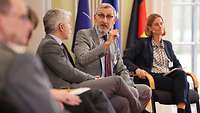 vier Personen sitzen auf einer Bühne
