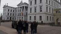 Eine Menschengruppe steht während einer Stadtführung vor einem imposanten Gebäude.