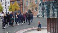 Eine Menschgruppe steht vor einem dekorativem Brunnen in Schwerin.