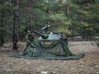 Zwei Soldaten bauen eine Panzerturm-Attrappe in einem Waldstück auf