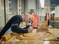 Ein Mann arbeitet an einem Modell aus Holz in einer Werkstatt