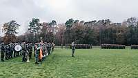 Eine Militärkapelle ist am Rande des Appellplatzes angetreten, im Hintergrund sind weitere Soldaten angetreten.