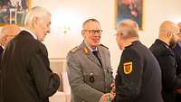 Mehrere Personen in Uniform begrüßen sich.