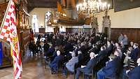 Blick in die Obere Rathaushalle mit Bremer Flagge und besetzten Stuhlreihen