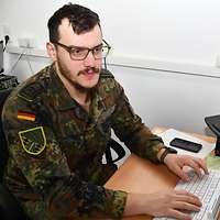 Ein Soldat sitzt am PC und arbeitet.