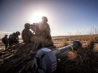 Draußen auf einem Feld knien vier Soldaten mit einer Panzerabwehrwaffe.
