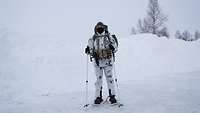 Ein Soldat steht in voller Ausrüstung im Schnee.