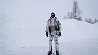 Ein Soldat steht mit einem Teil der Ausrüstung im Schnee.