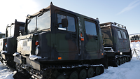 Zwei Kettenfahrzeuge mit Tarnmuster stehen im Schnee.