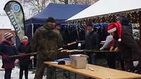 Vier Kinder stehen vor einem Grill und machen Stockbrot.