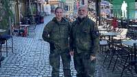 Eine Soldatin und der Militärpfarrer posieren in der Stadt für ein Foto.