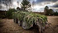 Auf einem mit Tannengrün getarnten Radpanzer befindet sich ein Maschinengewehr.