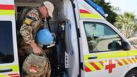 Ein Soldat in Uniform steigt hinten aus einem Krankenwagen aus. Er hat einen Rucksack in der Hand.