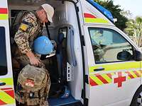 Ein Soldat in Uniform steigt hinten aus einem Krankenwagen aus. Er hat einen Rucksack in der Hand.