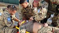 Der Verletzte wird von weiteren Soldaten auf die Trage gelegt. Der Arzt überprüft die Vitalwerte.