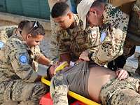 Der Verletzte wird von weiteren Soldaten auf die Trage gelegt. Der Arzt überprüft die Vitalwerte.