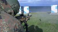 Ein Soldat zielt mit einem Maschinengewehr auf eine Zielscheibe in Richtung der freien Ostsee