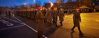 Mehrere Soldaten marschieren in Dunkelheit auf einem Paradeplatz im Rahmen eines Feierlichen Gelöbnis