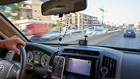 Blick durch die Frontscheibe: Ein Auto fährt durch eine Stadt