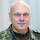 ein Soldat in Flecktarn mit weißem Haar im Porträt vor hellgrauem Hintergrund