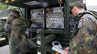 Zwei Soldaten arbeiten an einem Satellitensystem