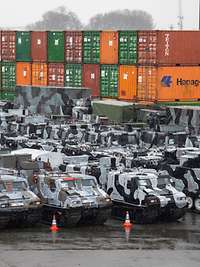 Militärfahrzeuge und Container warten auf die Verladung.